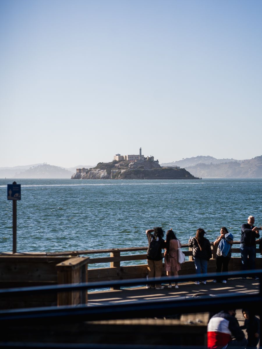 Turistas olhando a ilha de Alcatraz de um píer de São Francisco