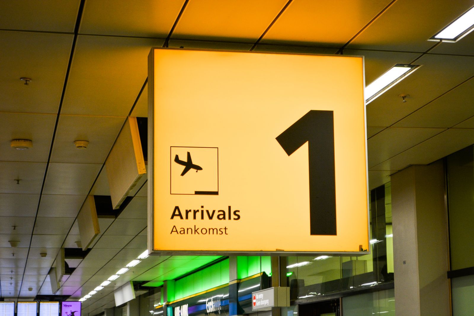 Teste o eSIM ainda no portão, antes da imigração e da esteira de bagagem: é lá que você vai precisar do mapa e do app de transporte. Placa amarela de desembarque, escrita Arrivals, no teto de um aeroporto