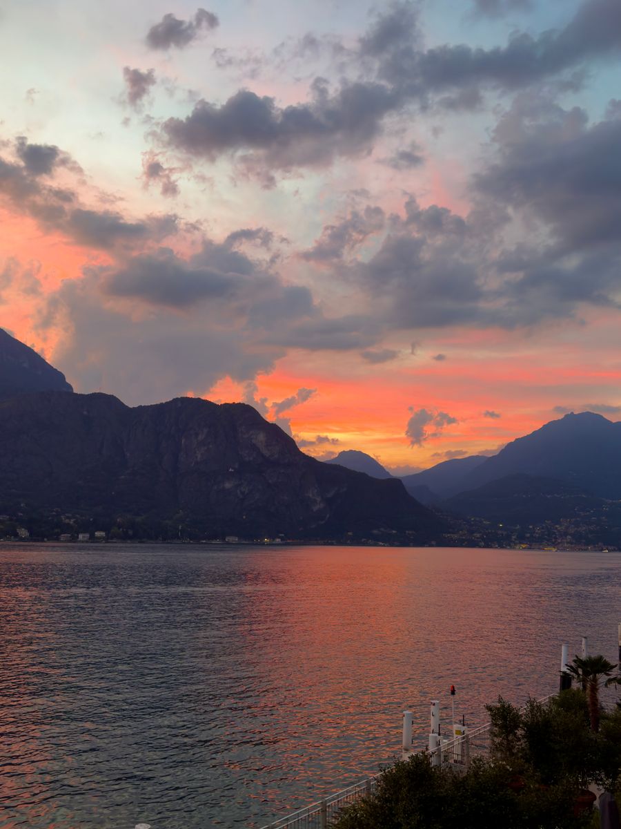 O Lago di Como ao entardecer, com montanhas e céu alaranjado