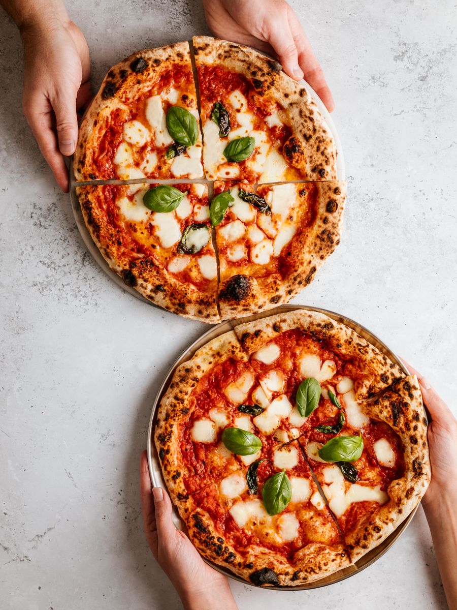 Duas pizzas margherita com manjericão sobre uma mesa clara