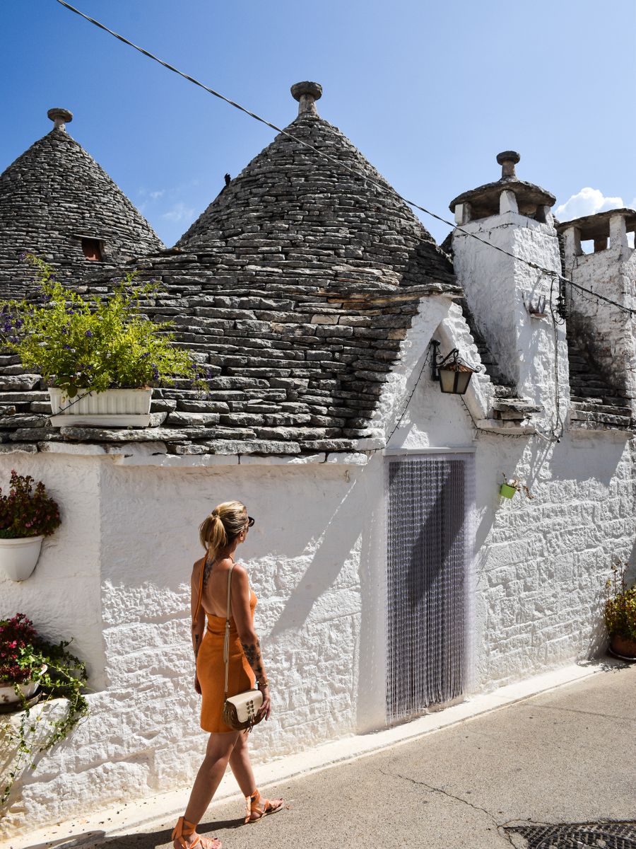 Uma mulher passa diante dos trulli, as casas de teto cônico de pedra de Alberobello