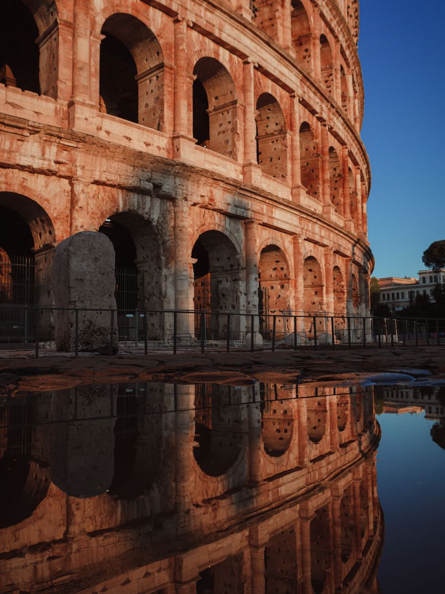 Os arcos do Colosseo refletidos numa poça ao fim da tarde