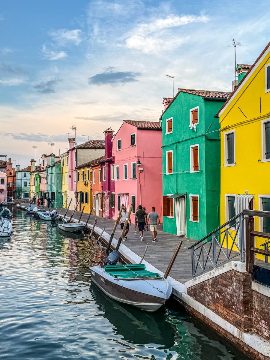 As casas coloridas de Burano ao longo de um canal com barcos