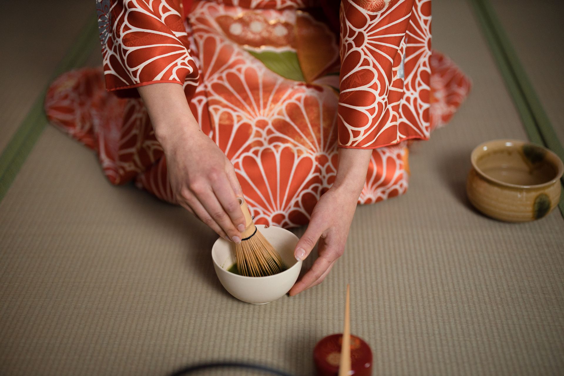 Uma pessoa de quimono prepara matcha numa cerimônia do chá tradicional