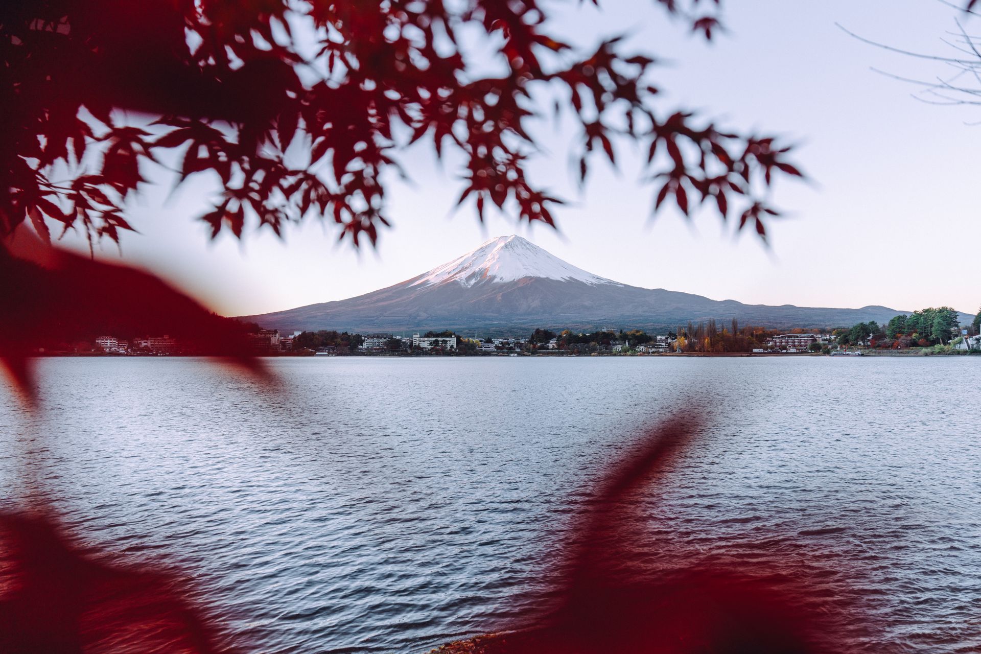 O Monte Fuji com neve no topo visto do Lago Kawaguchiko, emoldurado por folhas vermelhas de bordo