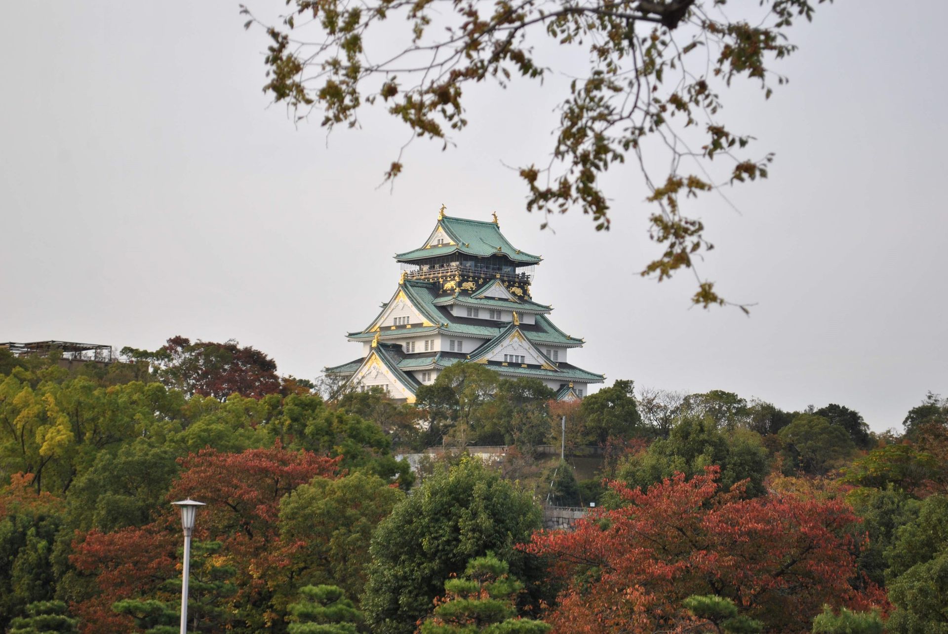 O Castelo de Osaka cercado de árvores de outono sob céu azul