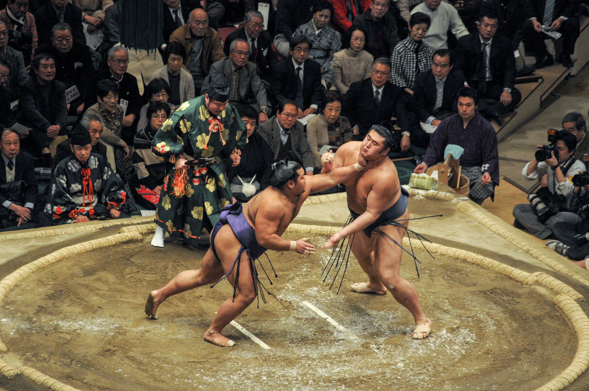 Lutadores de sumô se enfrentam no ringue diante da plateia num torneio no Japão