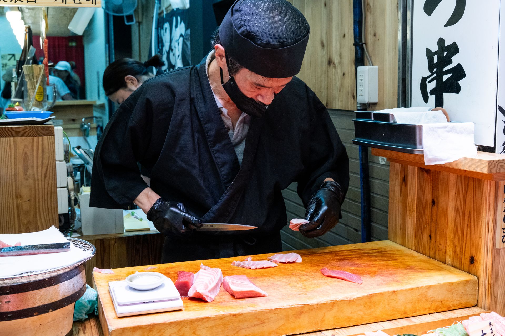 Um sushiman corta peixe fresco atrás do balcão de um restaurante japonês