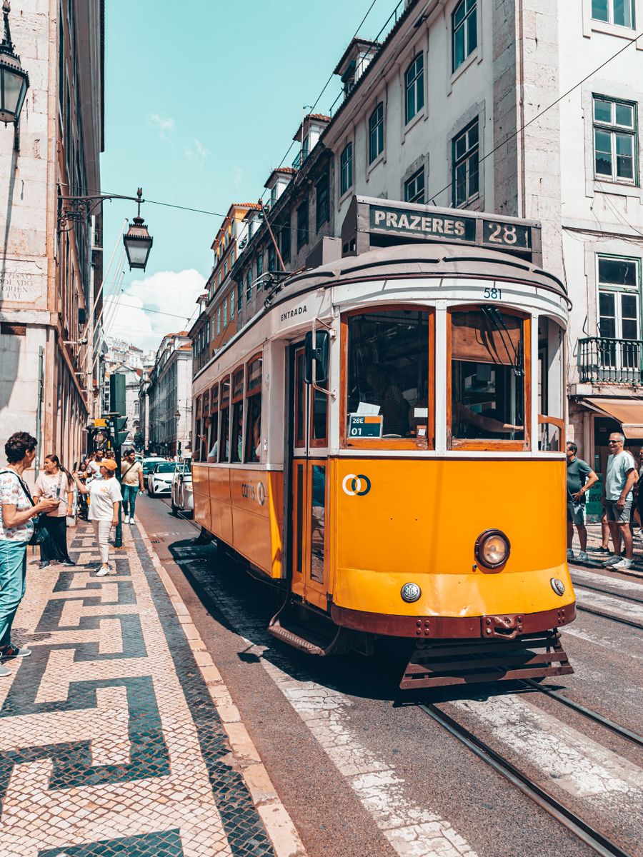 O elétrico 28, amarelo, numa rua de calçada portuguesa em Lisboa