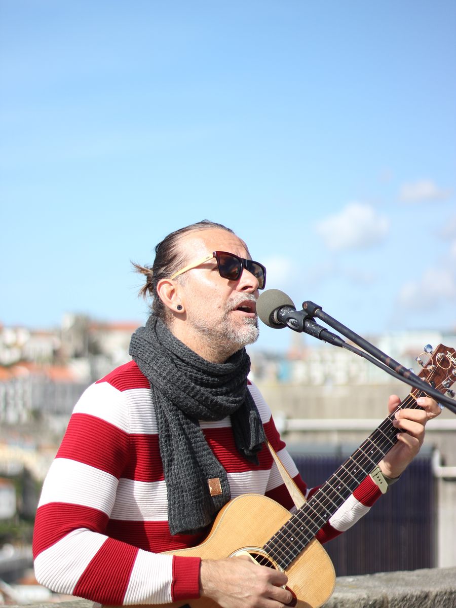 Músico de rua cantando com violão no Porto